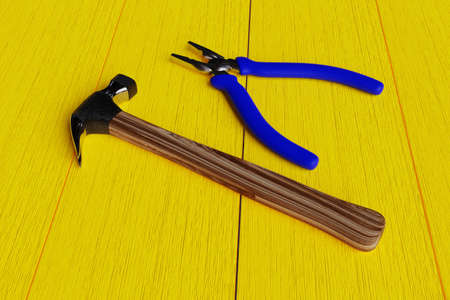 hammer and pliers on a yellow wooden background. hand tools. 3D rendering.