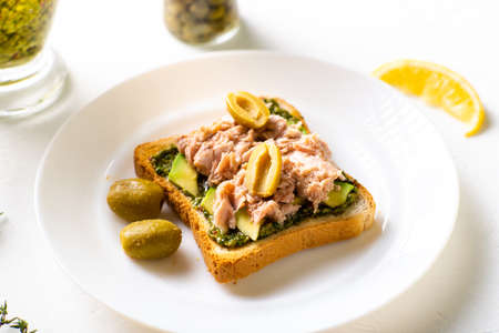 toast with tuna and avocado, olives with chimichurri sauce. On a white plate and white background.の写真素材