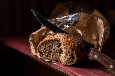 Sliced baguette with a bread knife. Bread made from buckwheat flour. Useful bread. dark background....