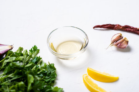 Sauce preparation. Lemon, olive oil, parsley, cilantro, garlic on a white background.の写真素材