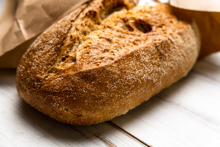 Fresh buckwheat bread on a white wooden background. A loaf of bread in a package.