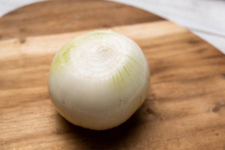 Whole onion peeled on a wooden board. Preparation for cooking.の写真素材