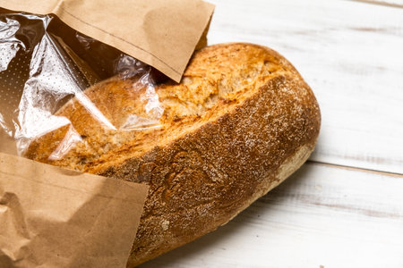 Fresh buckwheat bread on a white wooden background. A loaf of bread in a package.