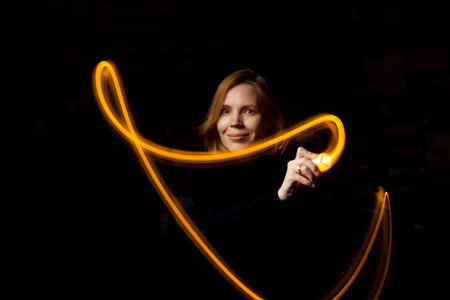 Write with light at long exposure in the dark. A middle-aged woman paints with a flashlight.の写真素材