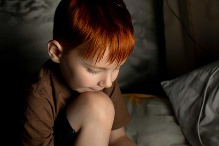 Portrait of a cute red-haired boy on a dark background.