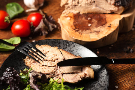 Chopped baked piece of meat with raw vegetables, green salad on a wooden background.の写真素材