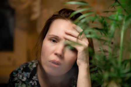 A middle-aged woman smokes. Surrounded by green plants. Fatigue, burnout, relaxation concept.の写真素材