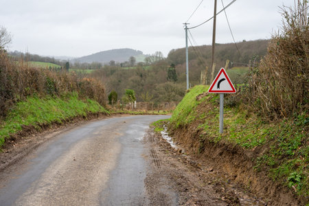 Road and road sign warning about a turn in the road. road safety concept. A sign in red triangle indicating a right turn in the roadの写真素材