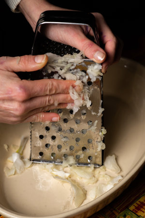 Female hands grate the onion. Preparing ingredients for cooking.の写真素材