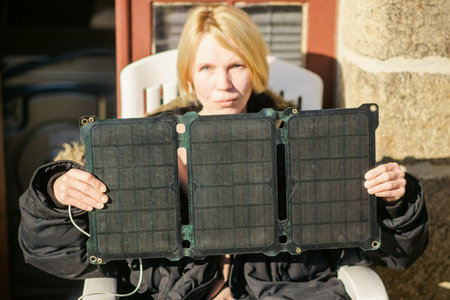 Portable solar battery in the hands of a woman. Alternative energy source concept.