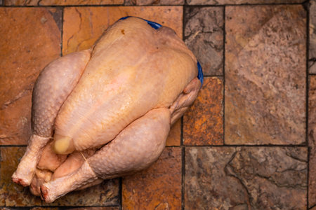 Whole whole chicken carcass on stone tile background.の写真素材
