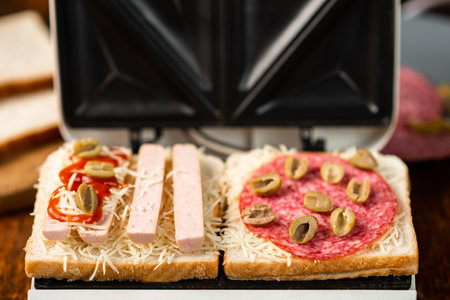 sandwich maker and cooking different sandwiches with sausage, olives, cheese, sausages.の写真素材