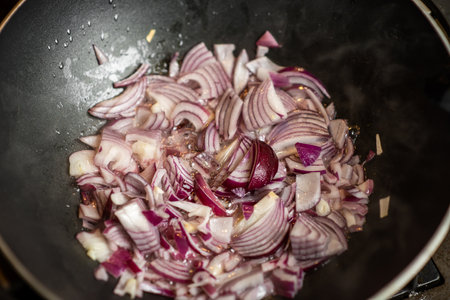 Fry the onion in a deep frying pan. Purple chopped onion is being prepared for cooking. top view.の写真素材