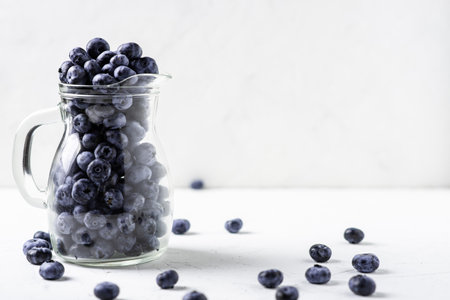 Blueberries in a glass jug on a white background. The benefits of berries, vegetarianism concept.の写真素材
