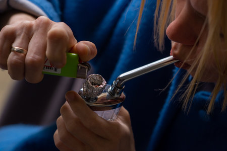 A woman lights a marijuana bong. Cannabis smoking device. A means of relaxation, concentration.の写真素材