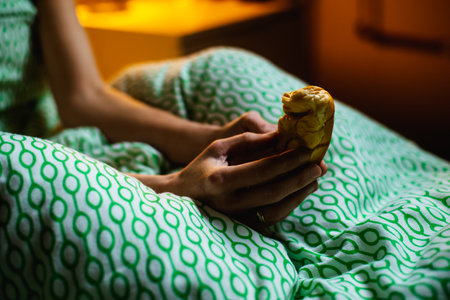 A woman in bed holds a bun in her hands that looks like a male phallus. Penis size, shape funny concept.の写真素材