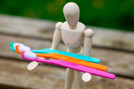Multi-colored toothbrushes in the hands of a human figure. Cleaning and caring for teeth concept.の写真素材
