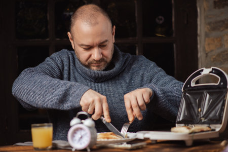 The man is having breakfast. An ordinary middle-aged man in a sweater is preparing to eat a sandwich...