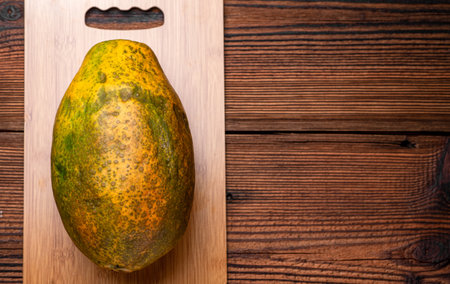 whole papaya on a wooden background. An imperfect-looking fruit with an uneven surface.の写真素材