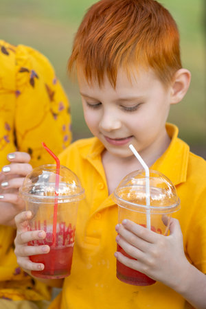 Young redhead boy holding lemonade outdoors. Summer refreshing drink.の写真素材