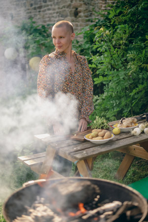 A woman prepares vegetables for the grill, cuts asparagus on the outdoors table on a sunny day. Vegetarian green grill.の写真素材