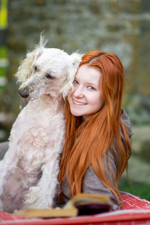 Cute red-haired girl smiling with an outdoors dog. Pets. Woman and dog together. Love for pets.