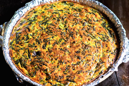 Freshly made homemade pie with spinach, cheese and egg. Vegetarian pie in shape on a dark...