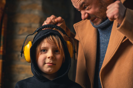 The father yells at the child. Young boy wearing headphones from noise. Home conflict, parenting problems concept.の写真素材