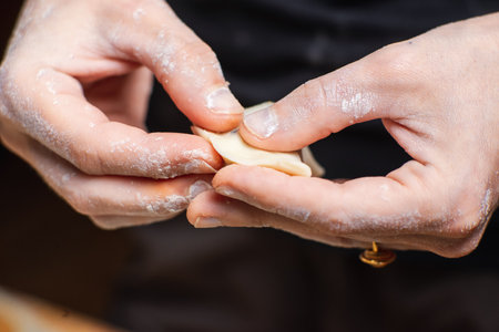 Sculpting dumplings close-up. Women's hands make dumplings stuffed with potatoes and mushrooms.の写真素材