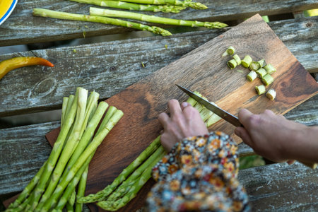Women's hands cutting asparagus. Preparation for green grilling. Vegan meals.の写真素材