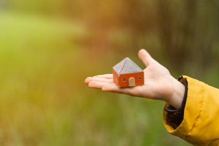 A toy house in the hands of a child. The concept of buying, renting, mortgage housing.の写真素材