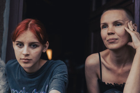 A middle-aged woman with a short haircut sits near her teenage daughterの写真素材