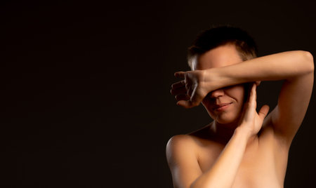 An image featuring a middle-aged woman with a short haircut against a black backdrop. She shields her face with her hands, conveying a sense of despair and depressionの写真素材