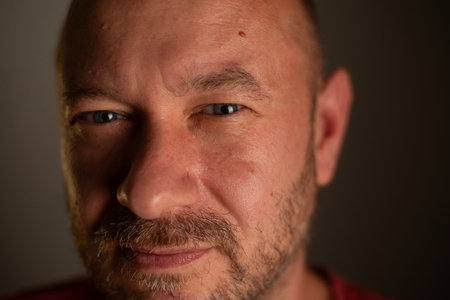 A close-up portrait capturing the friendly and welcoming nature of a 40-year-old unshaved man with a...