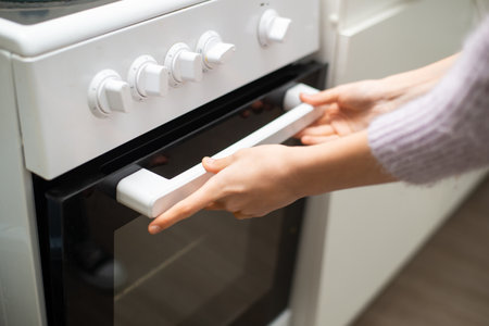 Woman's hands open the oven doorの写真素材