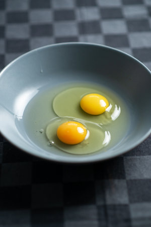 Two raw chicken eggs in a plate on a dark background. Cooking for making foodの写真素材