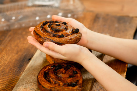Joyful treat: Child's hands reaching for a sweet round bun, a snack filled with love.の写真素材