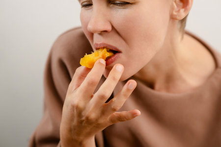 Flavorful break: A woman of charm and maturity enjoys a yellow plum, savoring the flavorful break of her fruity snackの写真素材