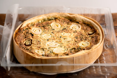 Rustic Charm: Rustic charm emanates from a leek and egg pie presented on a wooden board, evoking a...