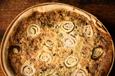 Flavorsome Creation: A beautifully baked leek and egg pie, arranged on a wooden table, captivates...