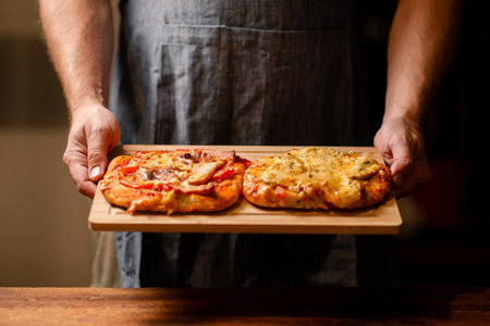 Rustic Pizza Moment: A snapshot of male hands showing two small homemade pizzas on a wooden board