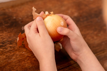 Earthy delights: a child's hands showcase the natural beauty of a whole red onion, highlighting the nutritional advantages on a rustic wooden backdropの写真素材