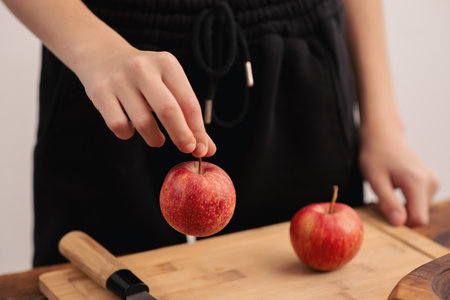 Woman's hands and fresh red apples on a wooden backdrop showcase the culinary delight of healthy...