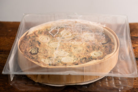 Culinary Symphony: A symphony of flavors is embodied in a leek and egg quiche placed gracefully on a wooden surfaceの写真素材