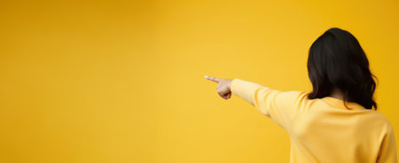 A woman's hand gestures towards an empty space on a vibrant yellow background, creating a lively setting for your text or designの素材