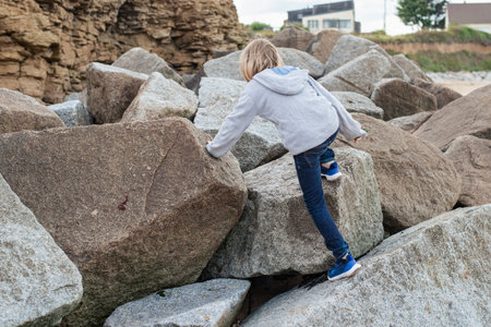 A young boy climbing onto large rocksの写真素材