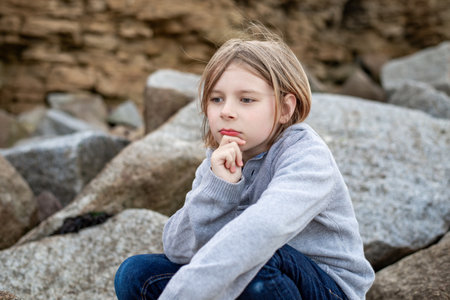 In a moment of reflection, a 10-year-old boy contemplates on the large stonesの写真素材