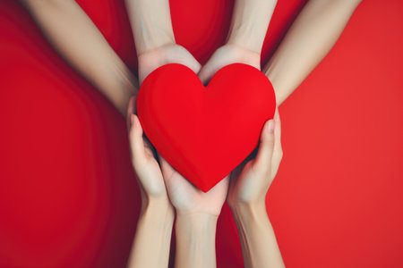 Red heart symbolizing mutual care and solidarity held by numerous handsの素材
