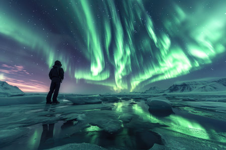 A stunning view of the Northern Lights illuminates the night sky with vivid green and purple hues, while a frozen landscape mirrors this celestial magic.の素材