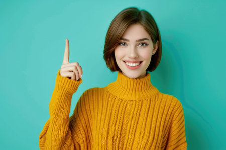 A young woman with a bob haircut smiles as she points directly at the viewer while wearing a bright yellow sweater.の素材